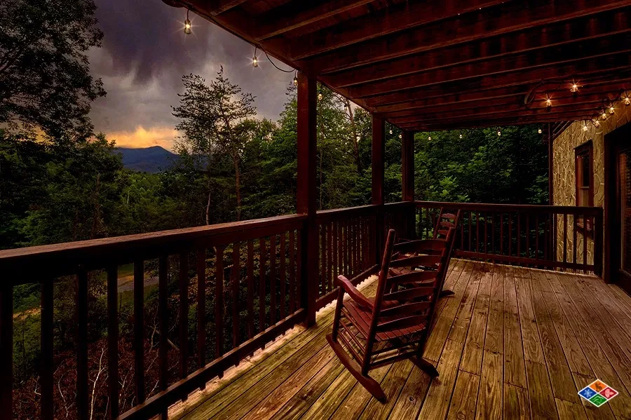 Covered deck at Cowboy Way with rocking chairs and sunset over the mountains